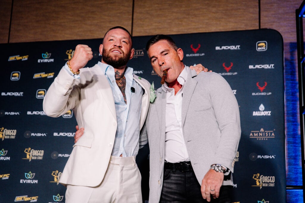 Conor McGregor set to host search for ‘World’s Baddest Man’ ahead of $25m tournament Conor McGregor in a white suit poses, fist up, with David Feldman who is smoking a cigar at a BKFC press conference