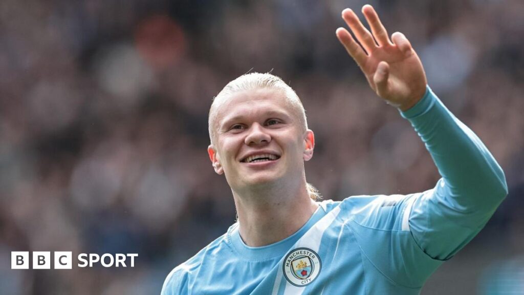 Erling Haaland, wearing Manchester City's light blue kit, celebrates his latest hat-trick by making a three-finger salute with his left hand